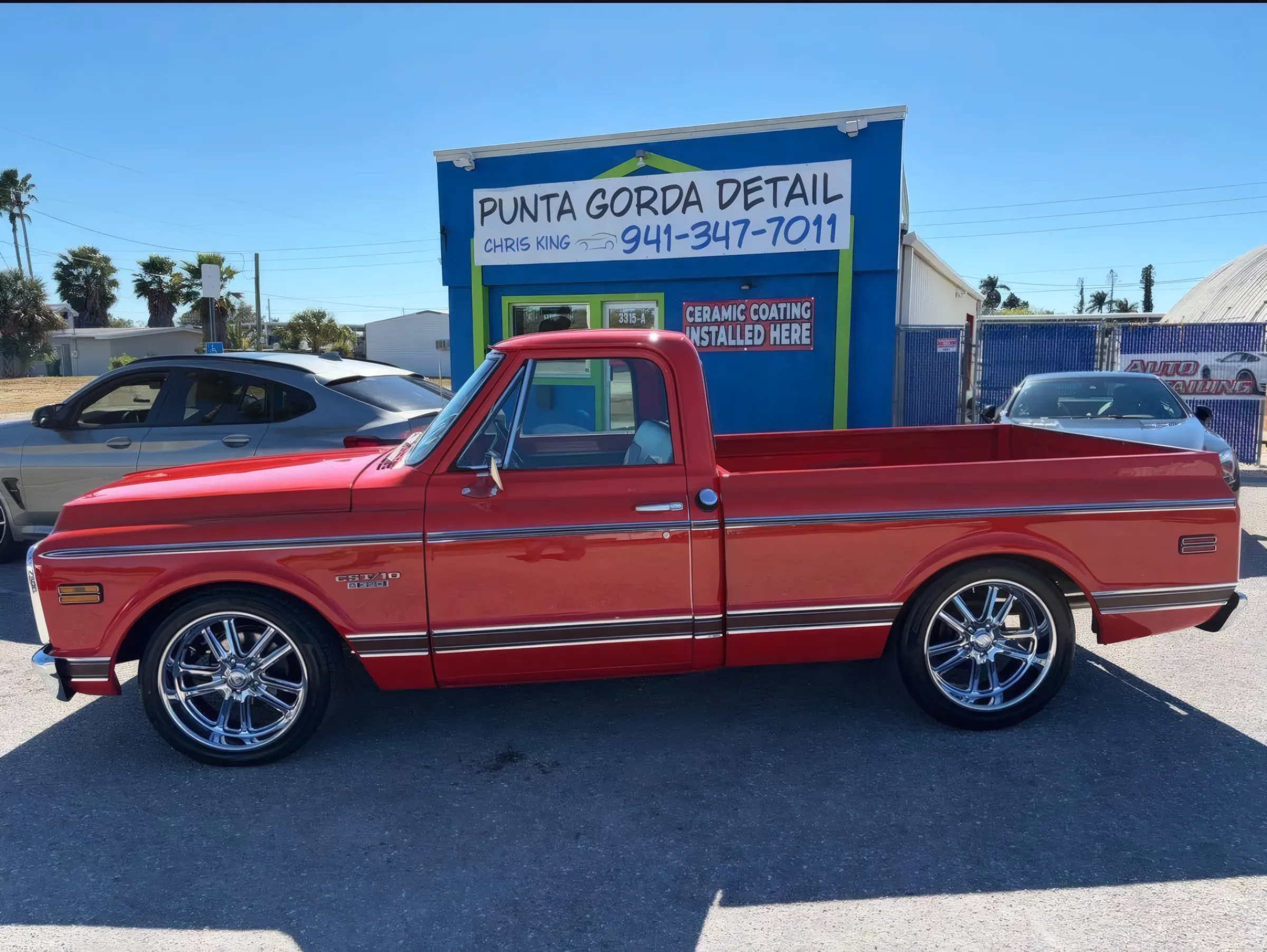 Red classic Chevy C10 pickup parked outside the Punta Gorda Detail shop, under a "Ceramic coating installed here" sign.